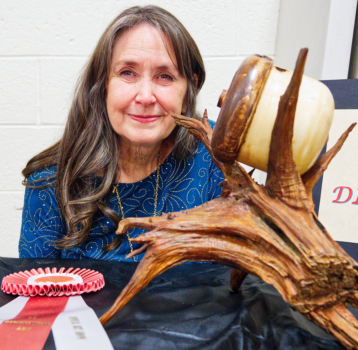 Trudy Haynes shows her brother’s award-wining sculpture displayed during last week’s Mineola League of the Arts annual art show.